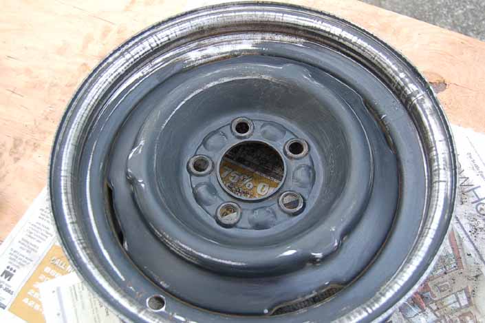 Photo shows the trailer wheel sanded and ready to be wiped clean and sprayed with 4 coats of primer from an aerosol spray can